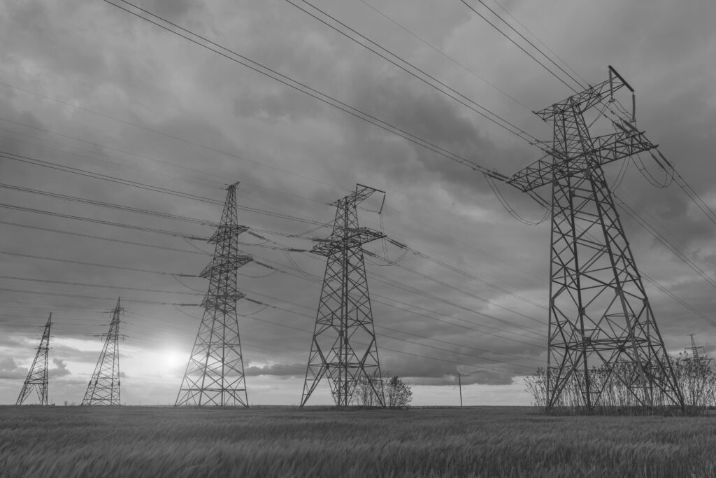 High-voltage power lines passing through a green field, on the background of a beautiful cloudy sky