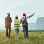 Three workers standing in a solar panel field